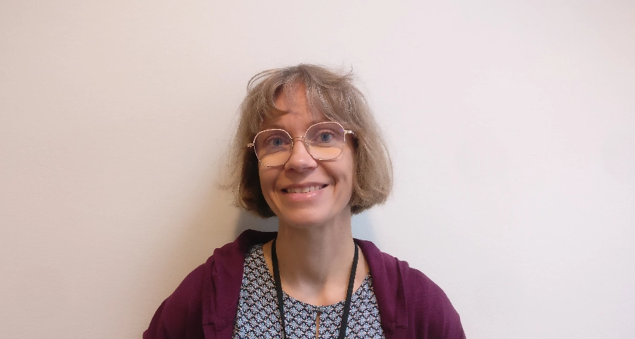 Hanna Guyot stands in front of a white wall.