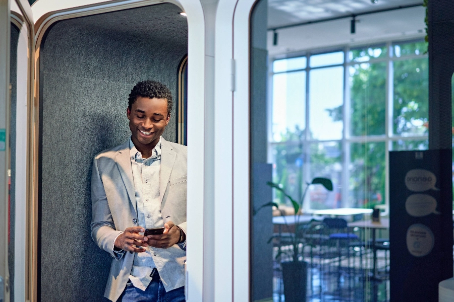 The man is talking on the phone in a phone booth. The man is talking on the phone in a phone booth.
