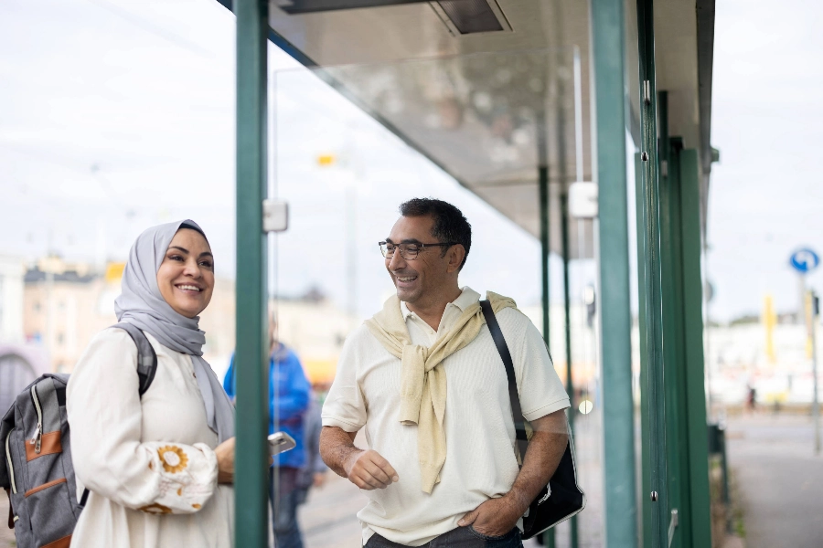 Two people are talking at a tram stop.