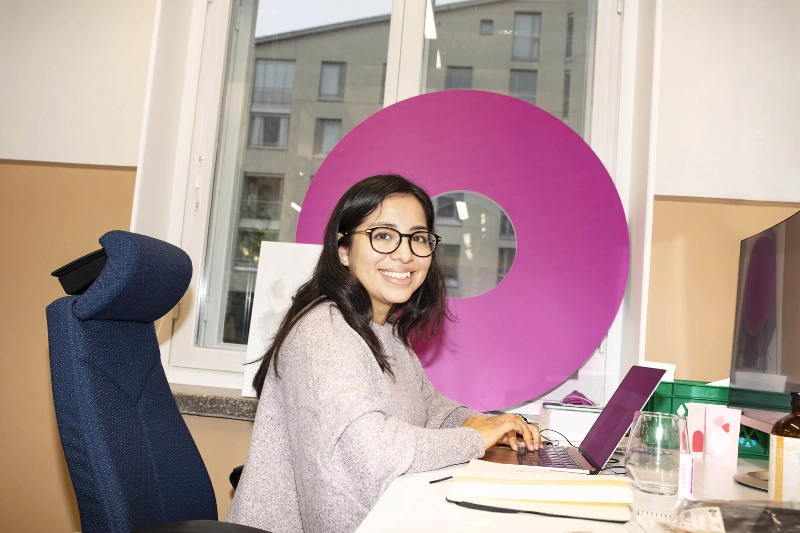 A woman smiles at the camera while working in her office. - N2 Albiino / Helsinki Partners