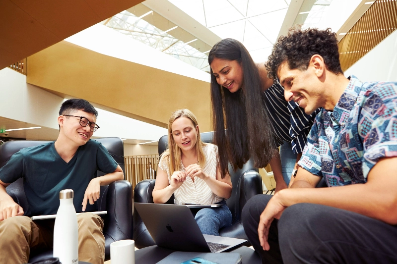 Four people sitting around a laptop discussing - Business Finland’s Work in Finland marketing only Four people sitting around a laptop discussing - Business Finland’s Work in Finland marketing only