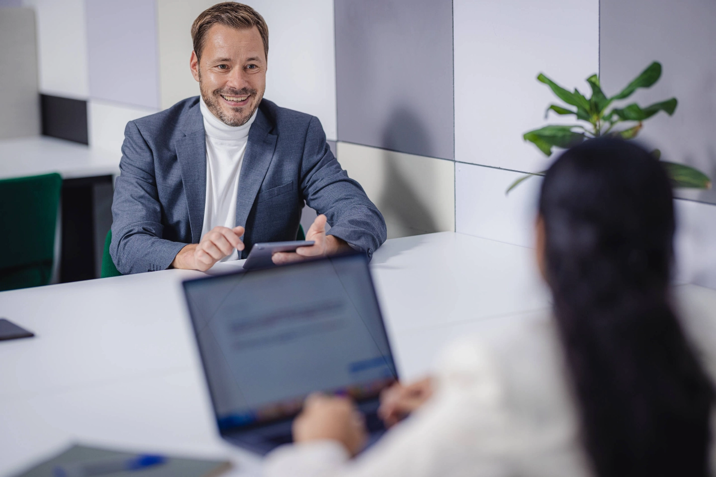 A business man with a mobile phone talking with a business woman at the table - Keksi / Markus Pentikäinen