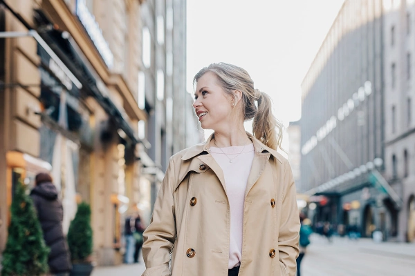 A smiling woman walks on the street. - Work in Finland / Elina Manninen A smiling woman walks on the street. - Work in Finland / Elina Manninen