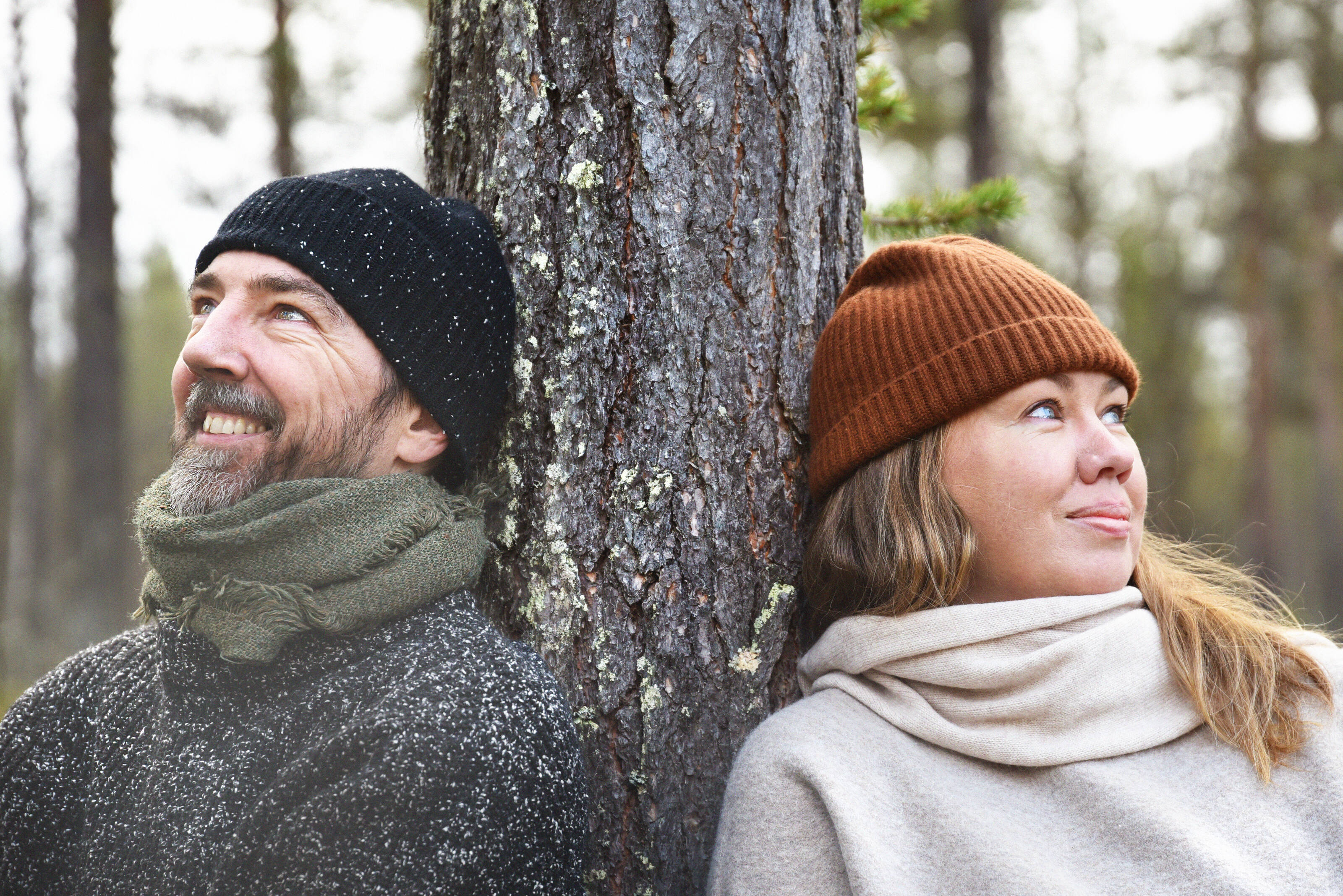 Two persons leaning against a pine tree