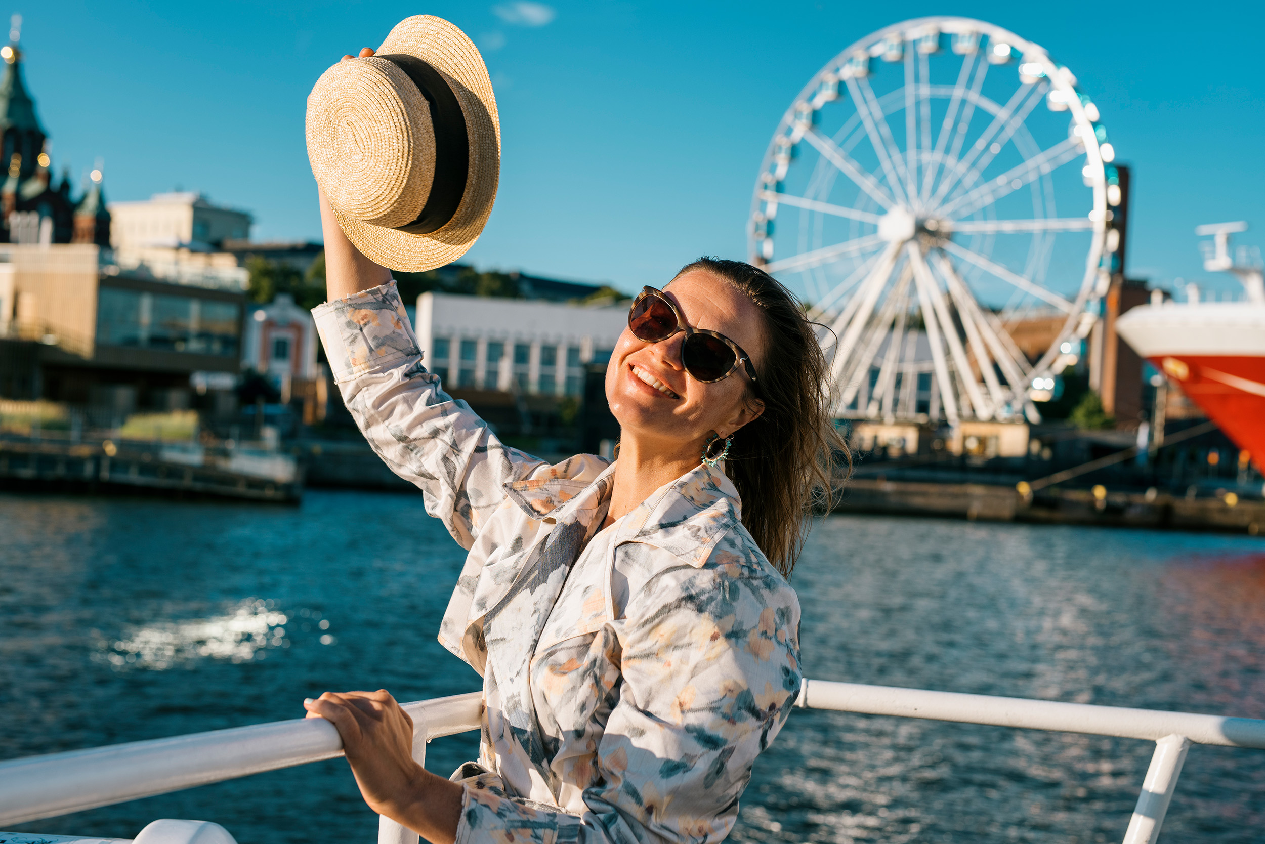 a woman waving her hat by the sea in the urban Helsinki