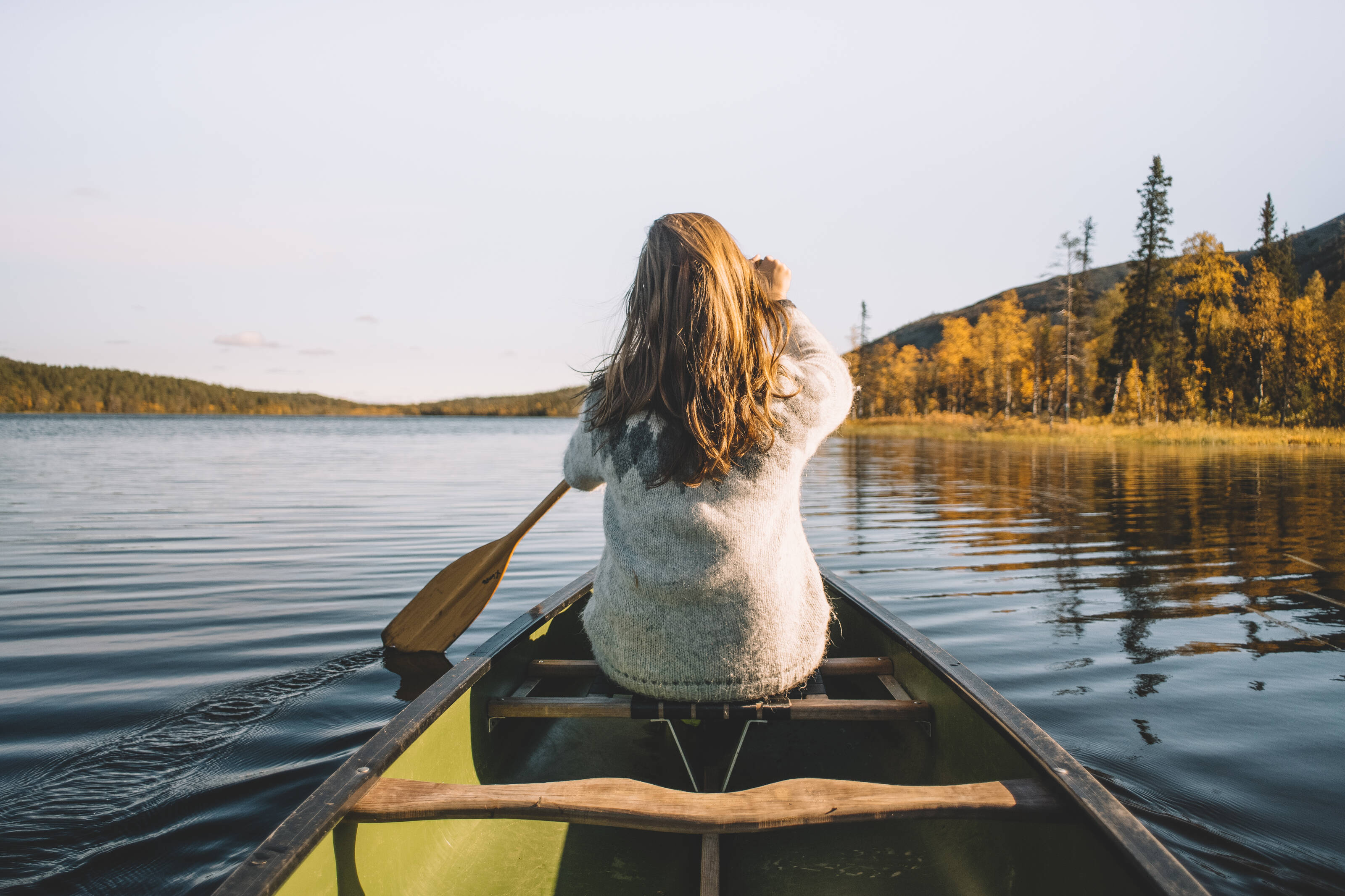 A women is paddling in a lake landscape in Finland
