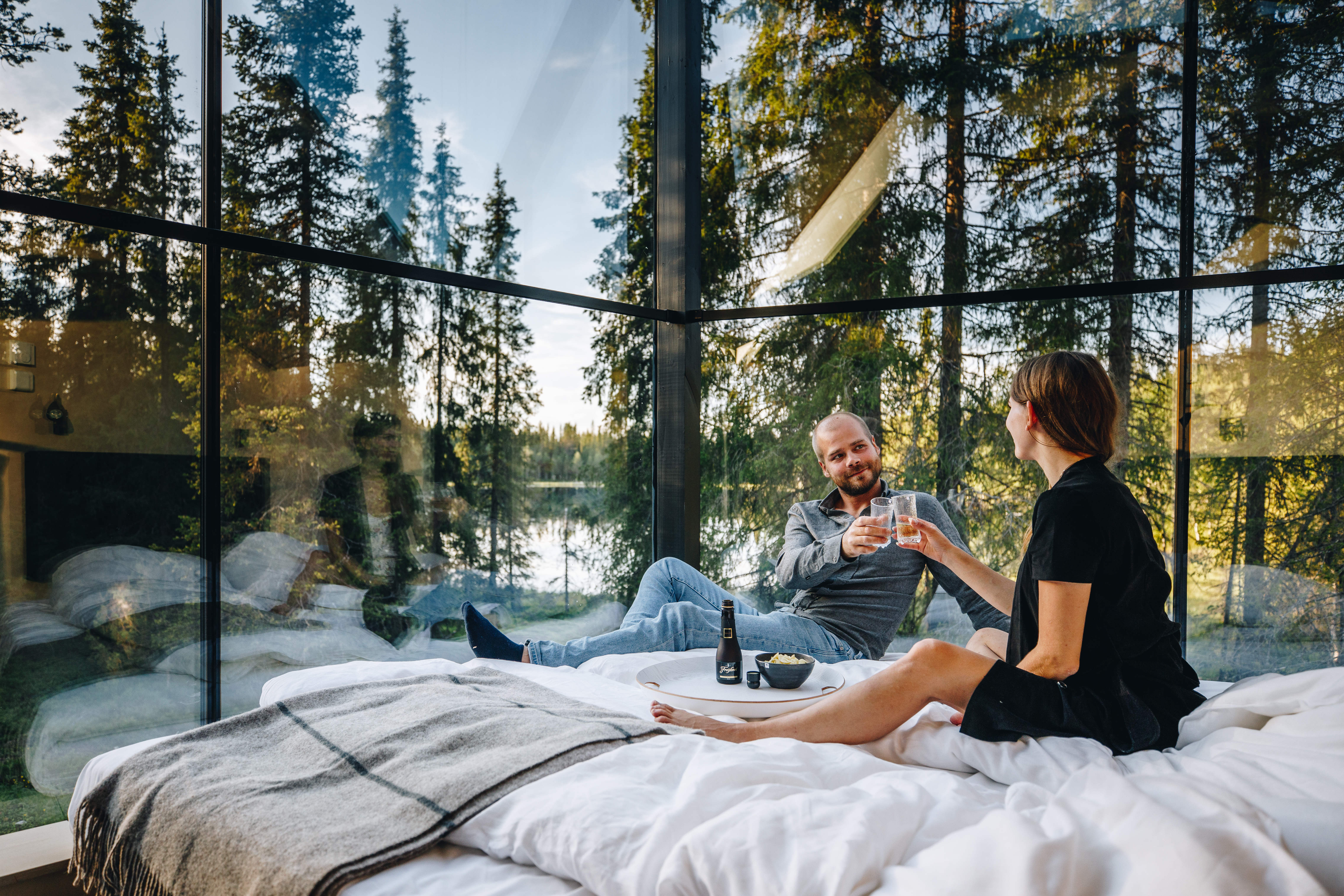 A couple having a good time in a glass hut in Lapland in the middle of the forest.