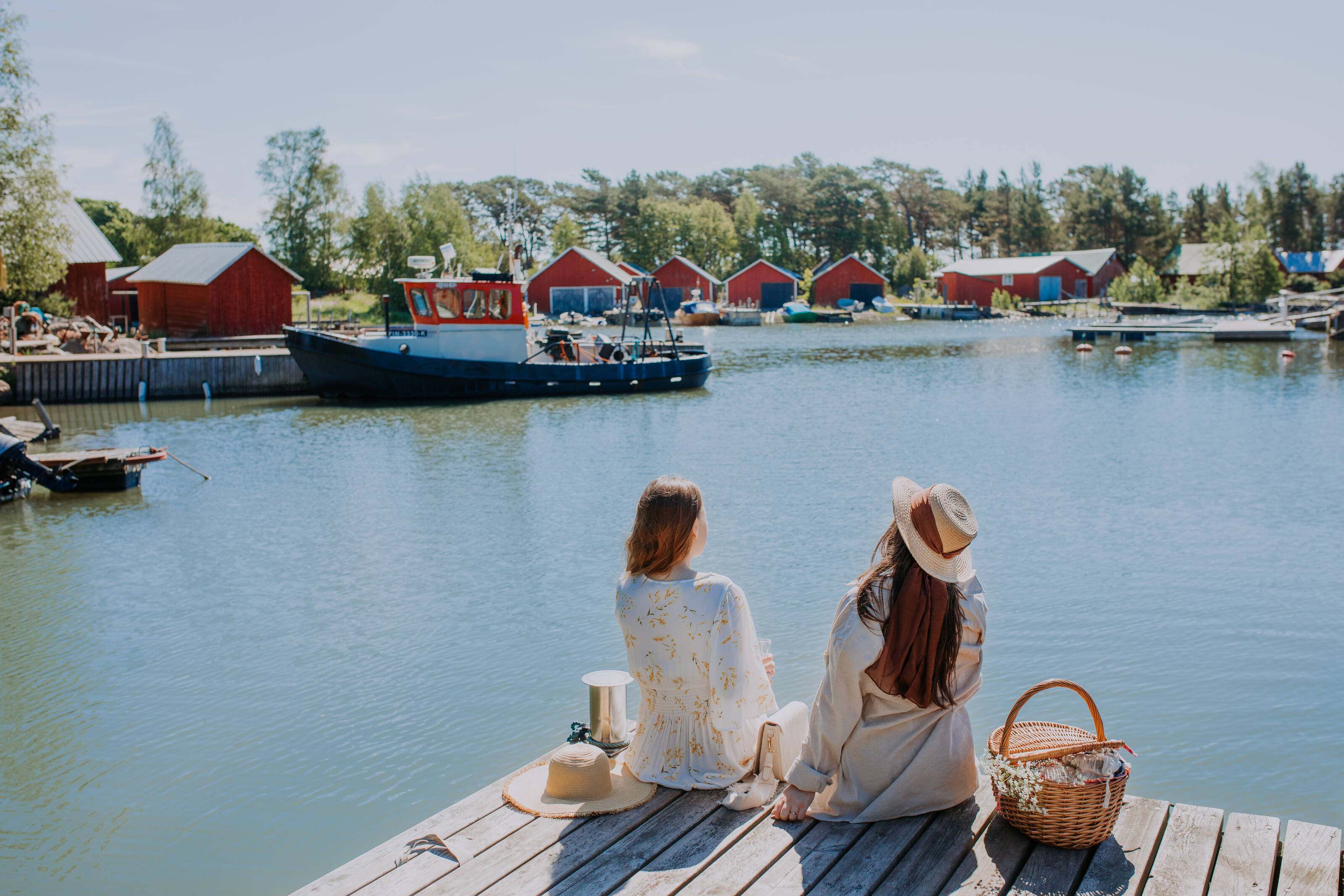 Two women sitting on a dock on a summer day in the Finnish Archipelago.