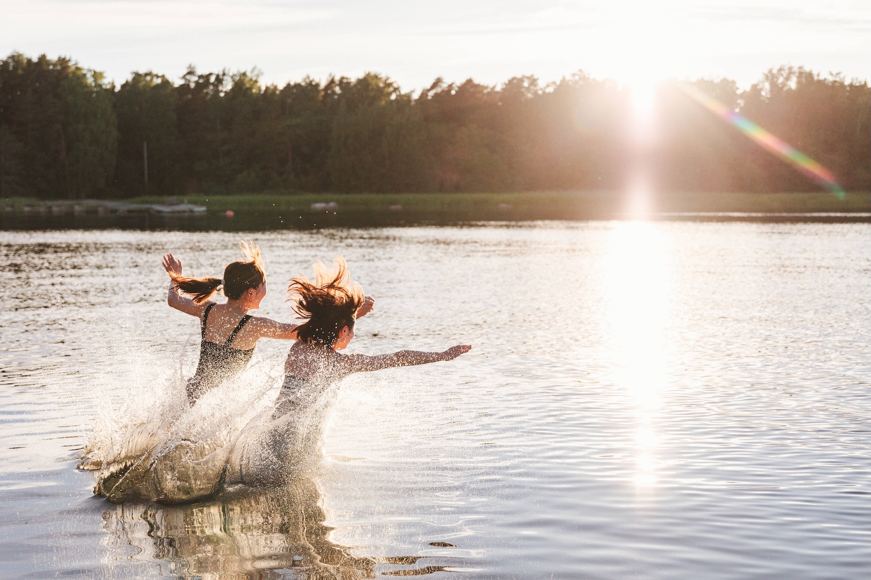 Deux personnes courant vers un lac finlandais en plein été, lors de la Saint‑Jean.