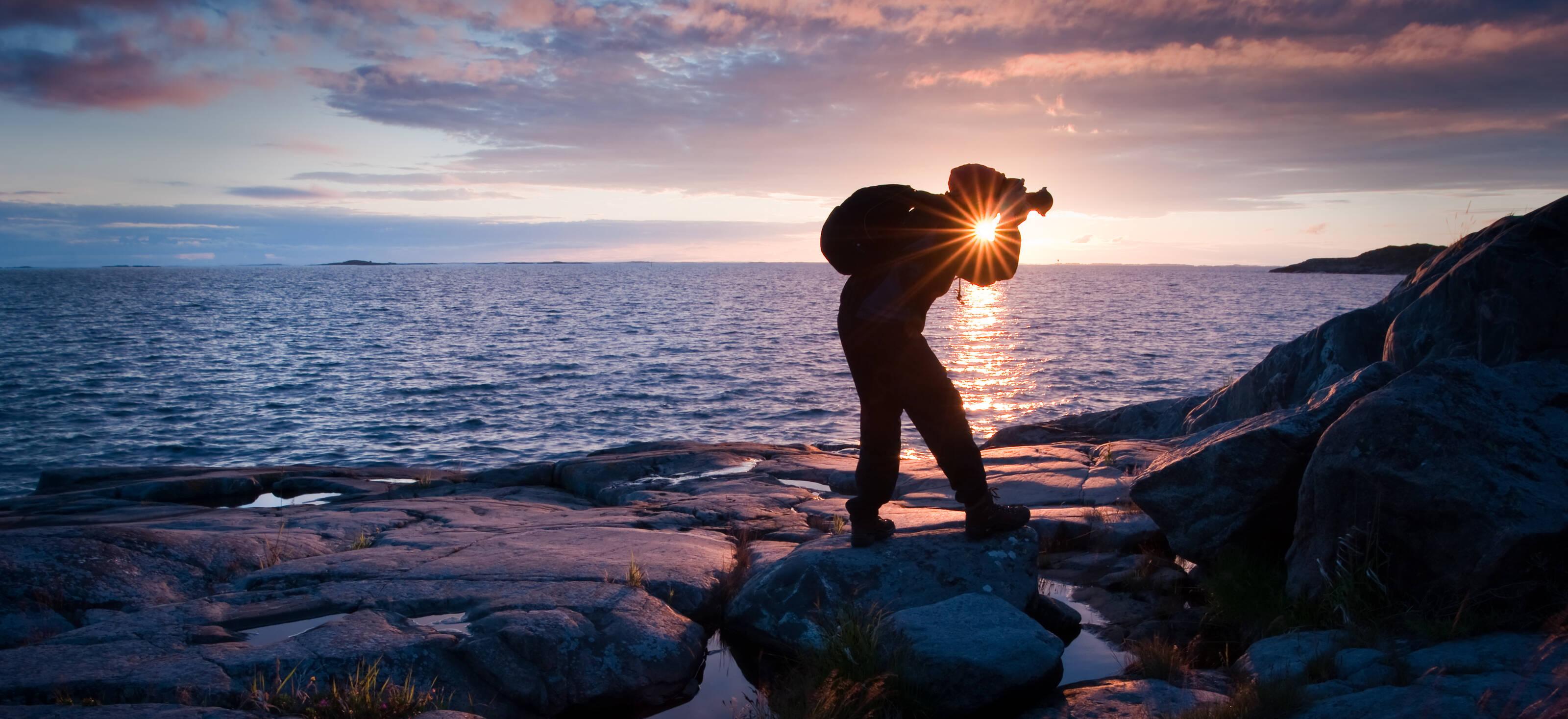 a man photographing the coast at sunset