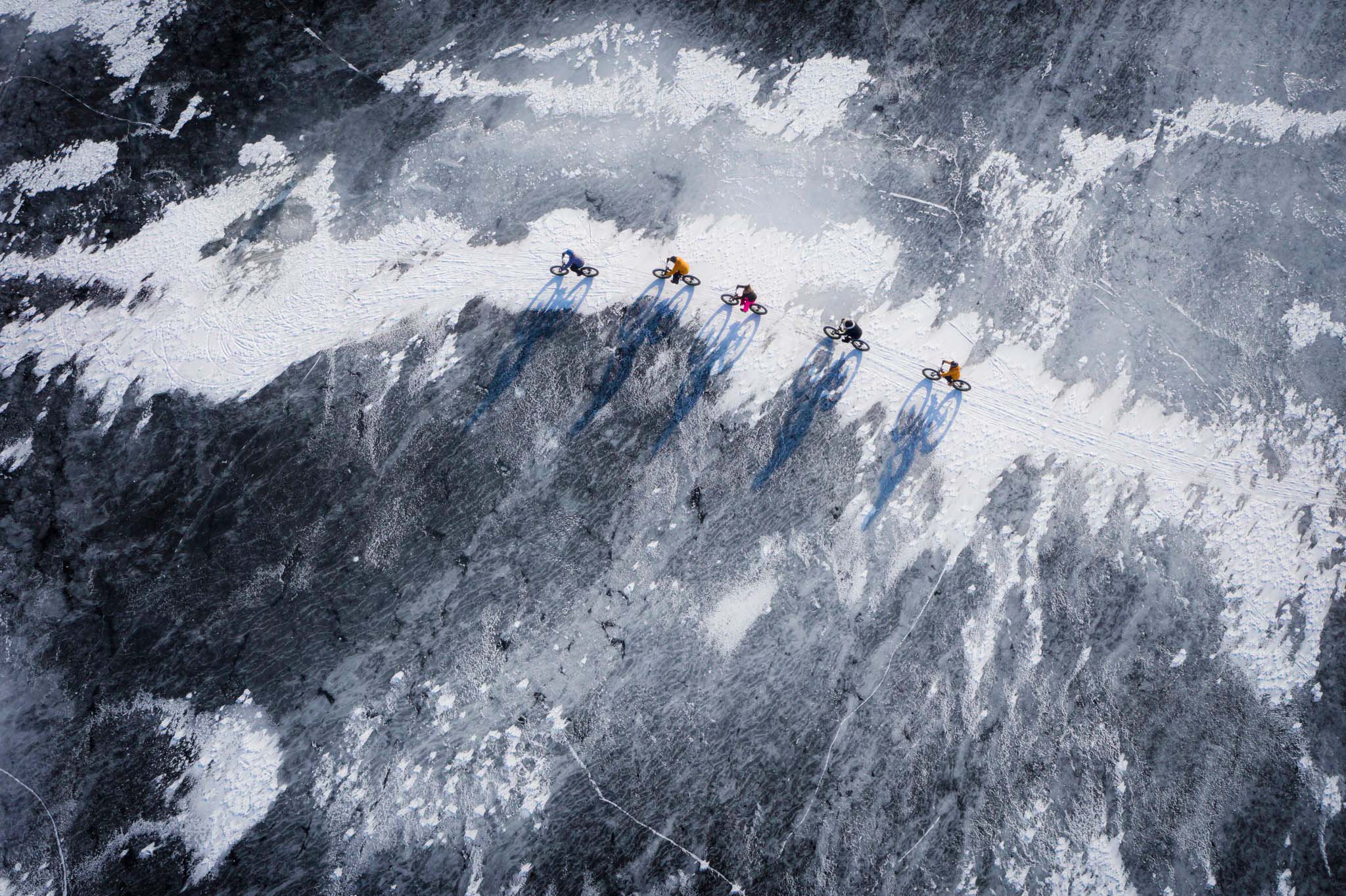 Group of cyclists riding on the frozen sea ice in Oulu, Finland.