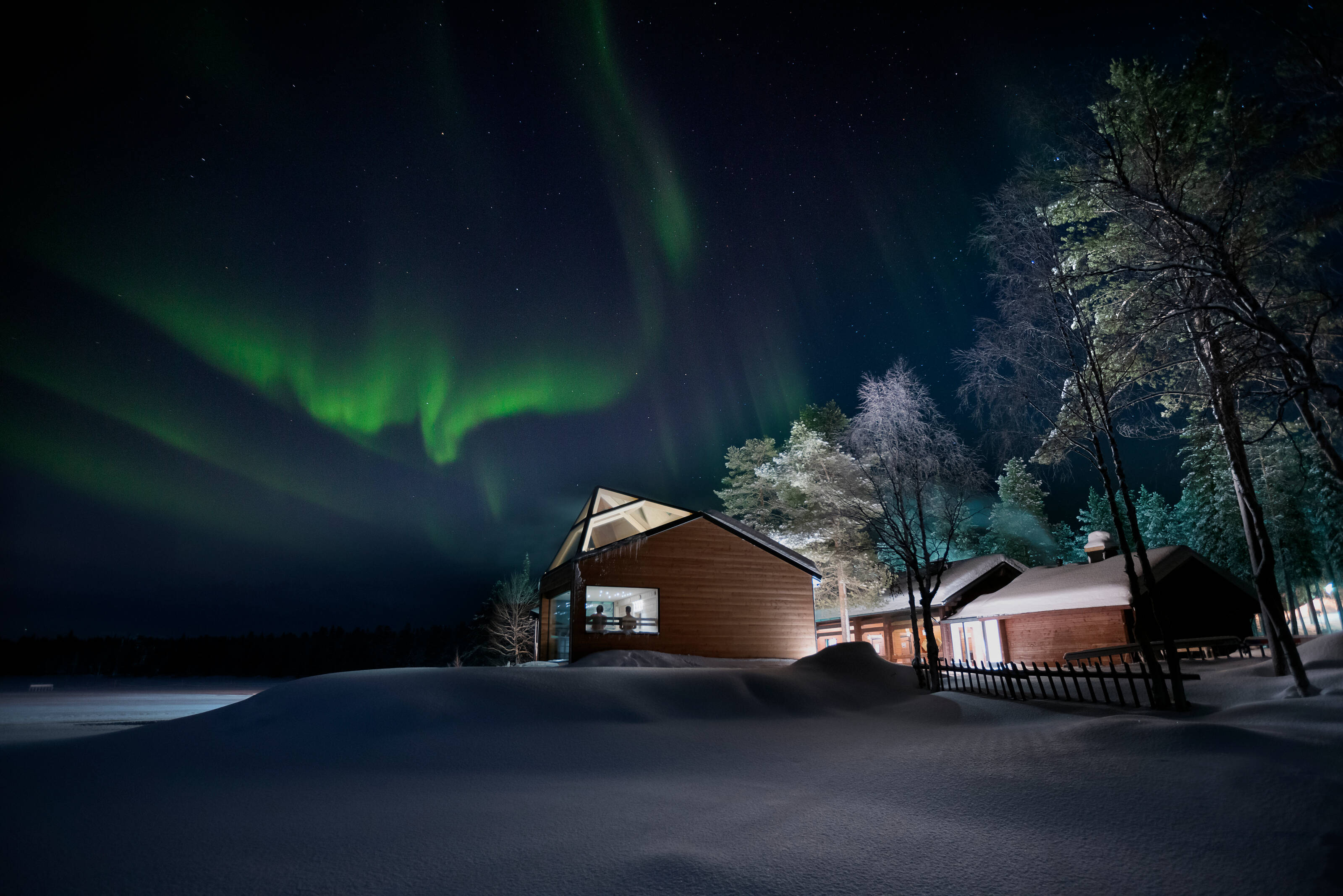 people inside sauna building watching the northern lights from a window