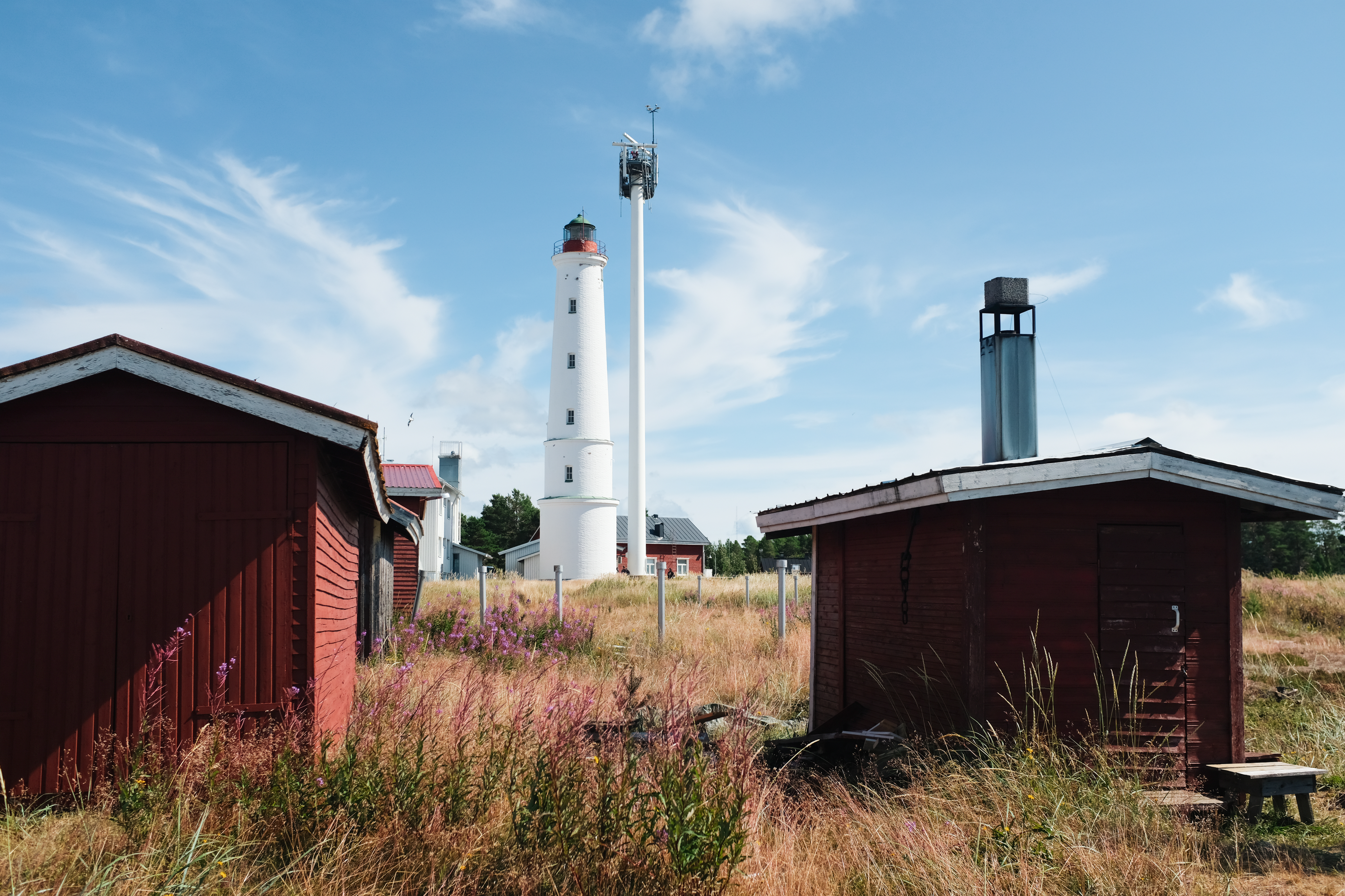a white lighthouse surrounded by wooden red houses