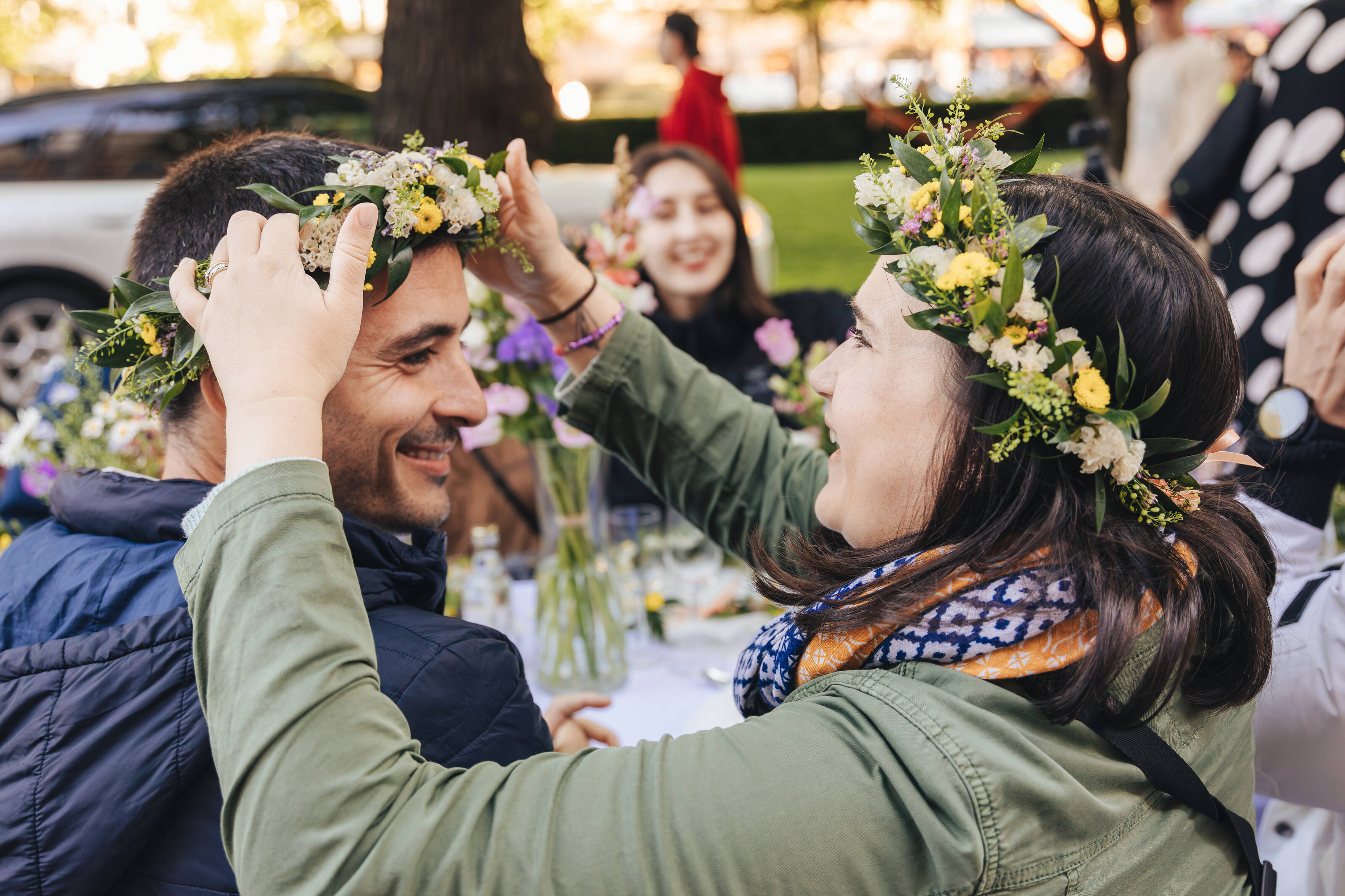 Participants of the Helsinki Happiness Hacks experience, wearing flower wreaths, basking in the sunshine at Esplanadi Park, Helsinki.